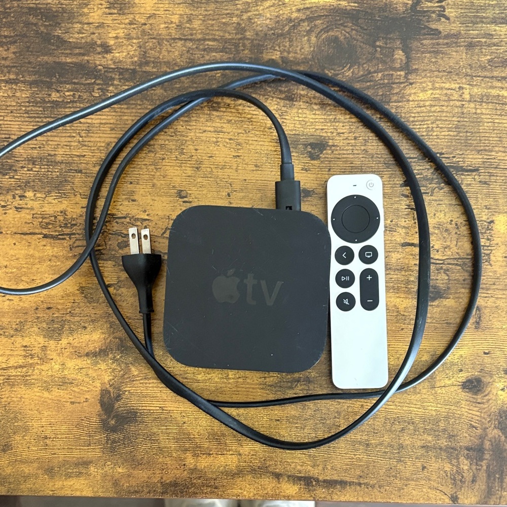 Apple TV streaming box with white Siri Remote and black power cable